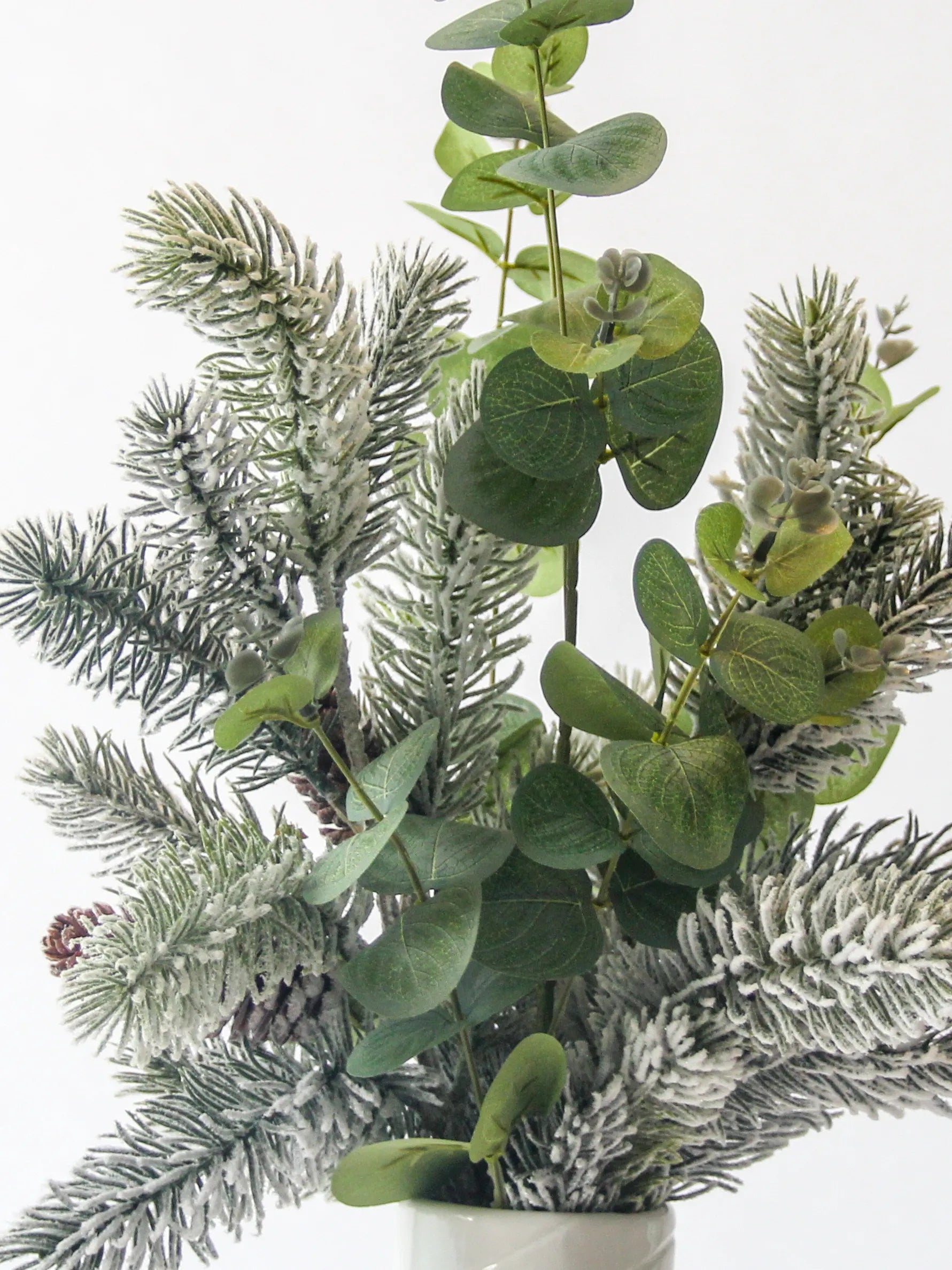 Zijden kerstboeket Silent Snow met besneeuwde Nordmann-tak en eucalyptus in witte candy vaas – 65 cm